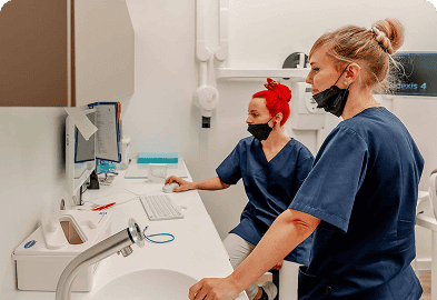 Zwei Frauen in Kitteln arbeiten an einem Computer.